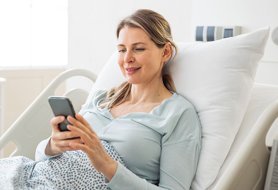 woman in hospital bed using her smart phone