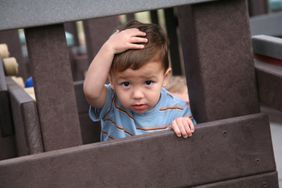 Older baby holding head after bumping it at the playground