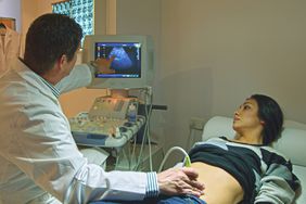 Doctor using ultrasound on pregnant person