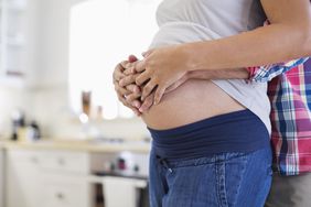 Partner holding pregnant person's belly