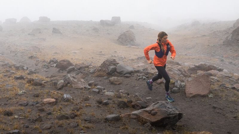 A women running in the mist on a trail.