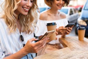 Two women getting coffee looking at their phones