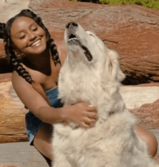 Dana Heath giving a white dog scratches outside in the sun