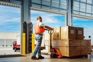 photo - Worker Pushing Pallet of Boxes in Warehouse