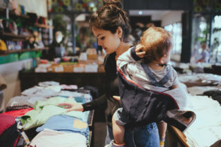 photo - Woman Carrying Her Baby and Clothes Shopping