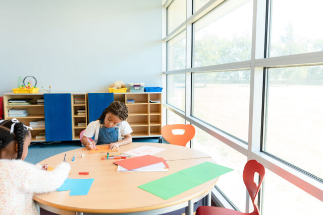 photo - Two Young Girls Coloring at Table in Classroom