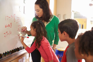 photo - Student phot - Writing on Board with Teacher in Elementary School Math Class