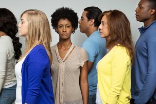 photo - Woman Looking at Camera Surrounded by Other People in Profile