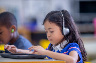 photo - Elementary Age Girl Using Digital Tablet in Classroom