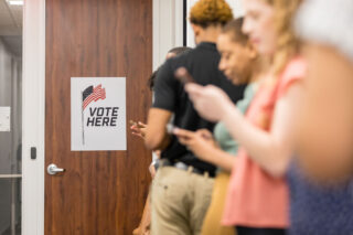 photo - Diverse Group Uses Phones While Waiting To Vote