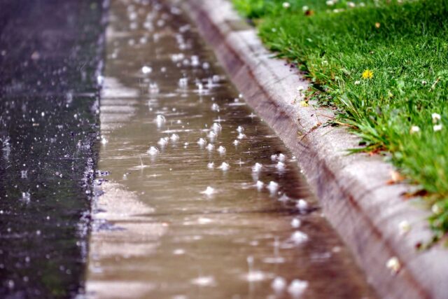 photo - Water Flowing along the Street Gutter during Heavy Rain