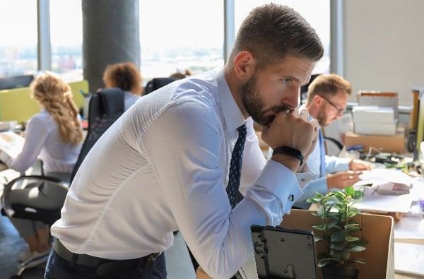 Professional man leans on desk and thinks about layoff at work