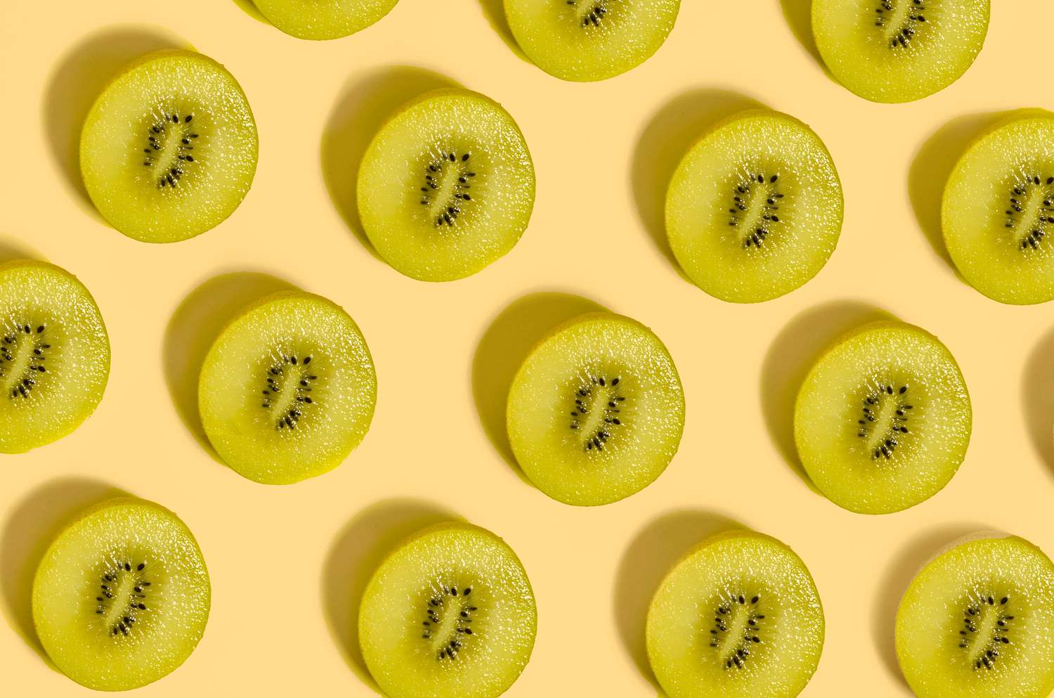Slices of green kiwi fruit on a pale yellow background