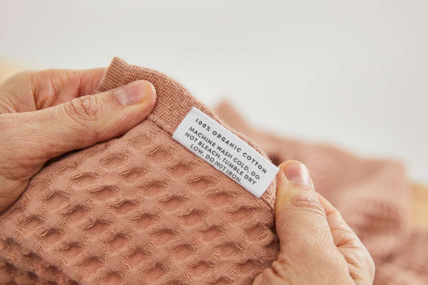 A hand showing the label on one of the items in The Citizenry Mara Organic Waffle Bath Towel Set