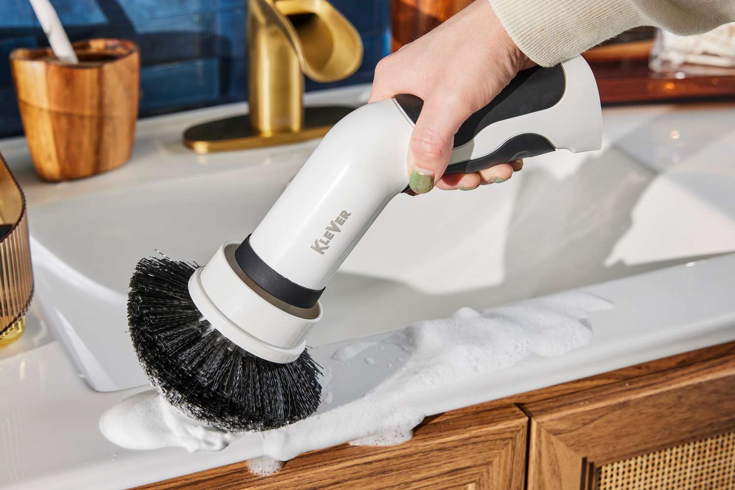 Close-up of hand cleaning a bathroom sink with a Klever Electric Spin Scrubber with 8 Brushes