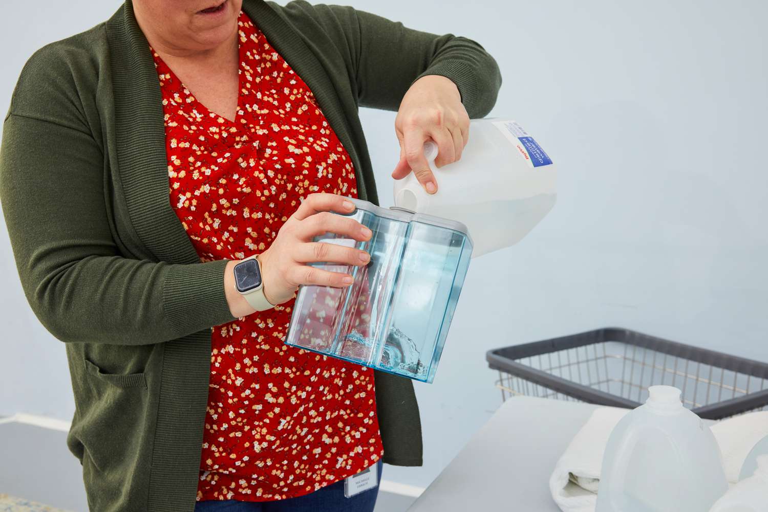 A person pours water into the Pure Enrichment PureSteam Pro Upright Clothes Steamer's water tank.