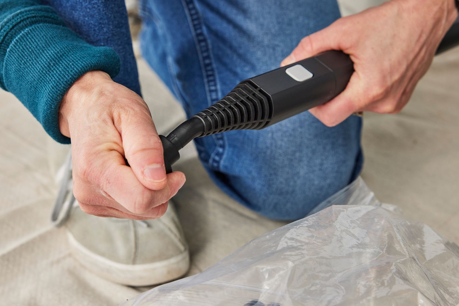 A person adds an attachment to the head of the Dupray NEAT Steam Cleaner