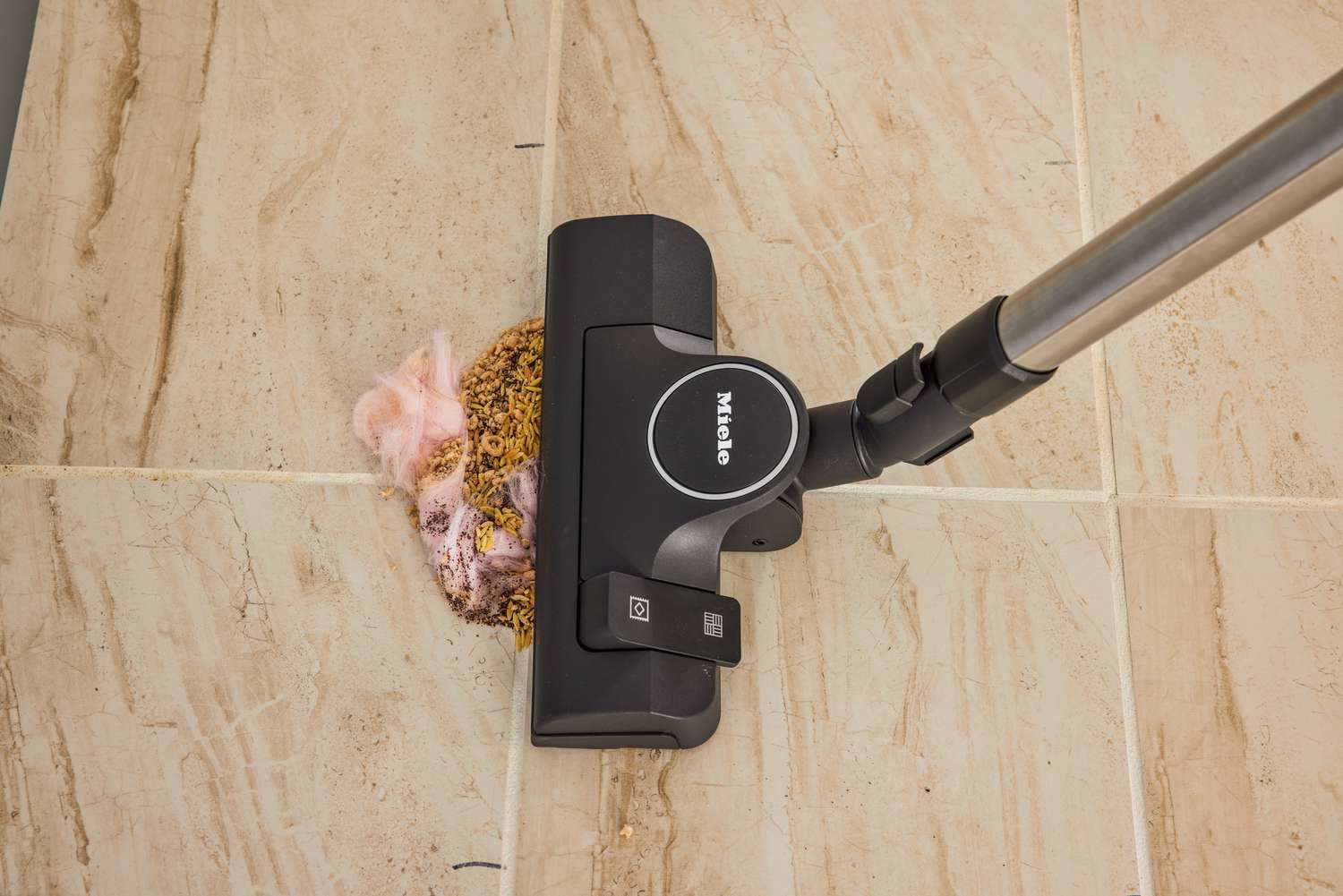 The Miele Classic C1 Pure Suction PowerLine Vacuum cleaning food off a tile floor.