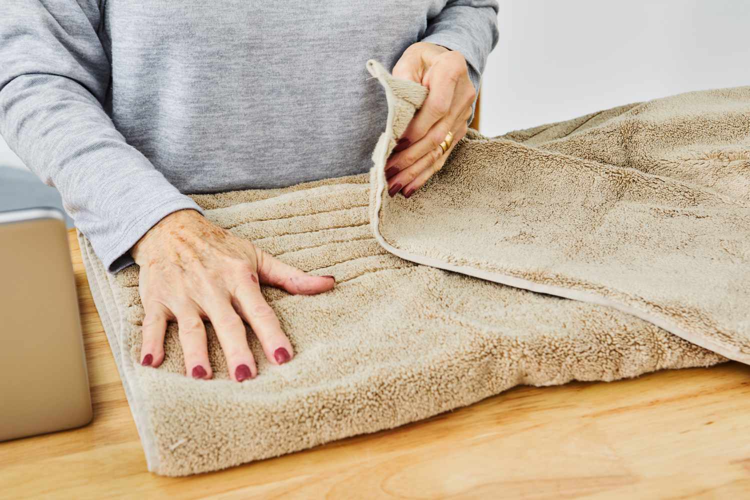 A person folding the Southern Living Turkish Cotton and Modal Bath Towel.