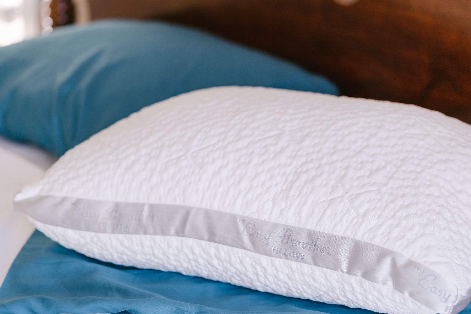  Nest Bedding Easy Breather Natural Pillow displayed on bed with nearby pillow covered by pillowcase