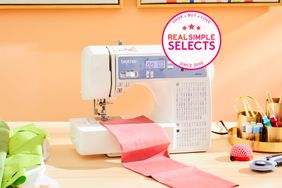 One of the best sewing machines, the Brother XR9550, siting on a table with fabric around it.