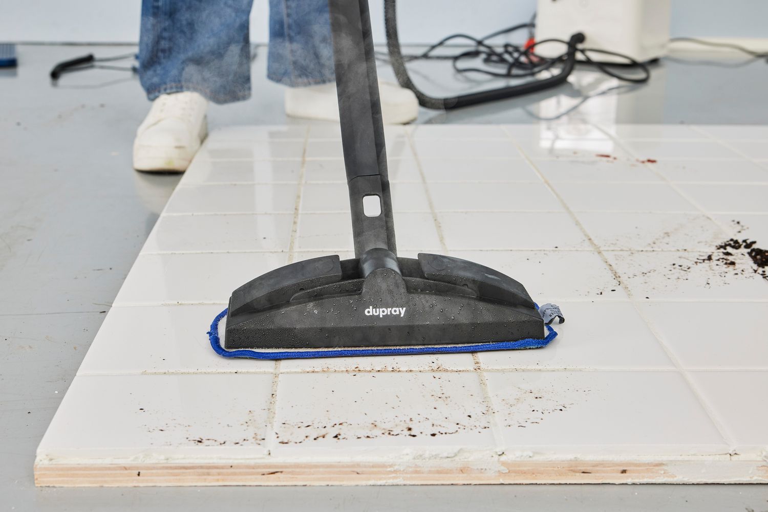 A person uses the Dupray NEAT Steam Cleaner to steam a tile floor