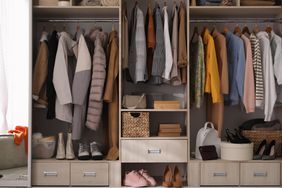 Wardrobe closet with different stylish clothes, shoes and home stuff in room