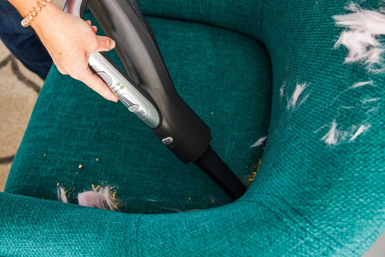 A person uses the Kenmore Elite CrossOver Bagged Canister Vacuum 21814 to clean a chair