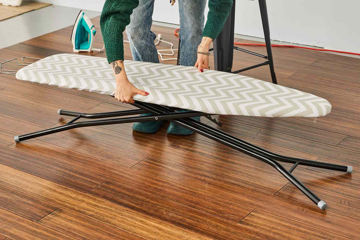 A person lifting the Amazon Basics Full-Size Ironing Board to assemble it