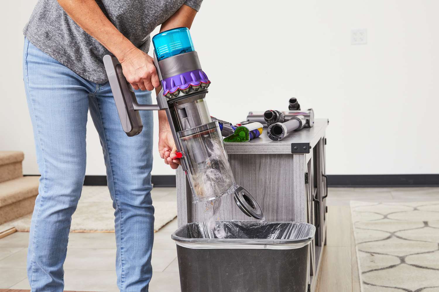 Person emptying dust into a trash can from the Dyson Gen5detect stick vacuum