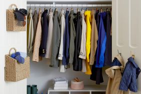 organized coat closet with baskets, hooks, a hanging rod and a shelf with blue and yellow baskets