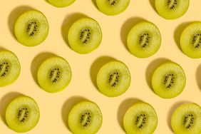 Slices of green kiwi fruit on a pale yellow background