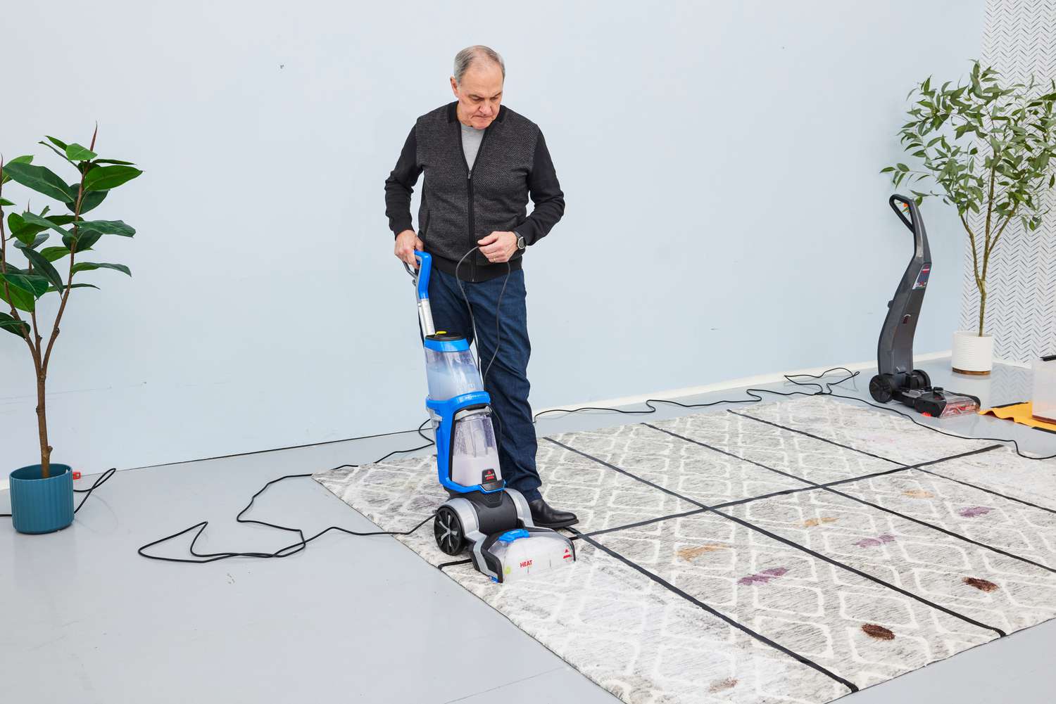 Person using a Bissell ProHeat 2X Revolution Pet Carpet Cleaner 35799 on a carpet with multiple stains on it