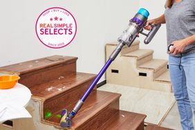 A person vacuuming wooden stairs using the Dyson Gen5detect Cordless Vacuum