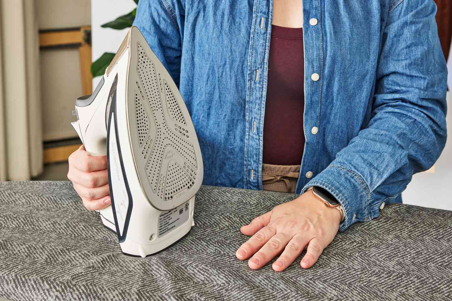 A person holding an iron with one hand and pressing on the Bartnelli Heavy Duty Ironing Board with the other