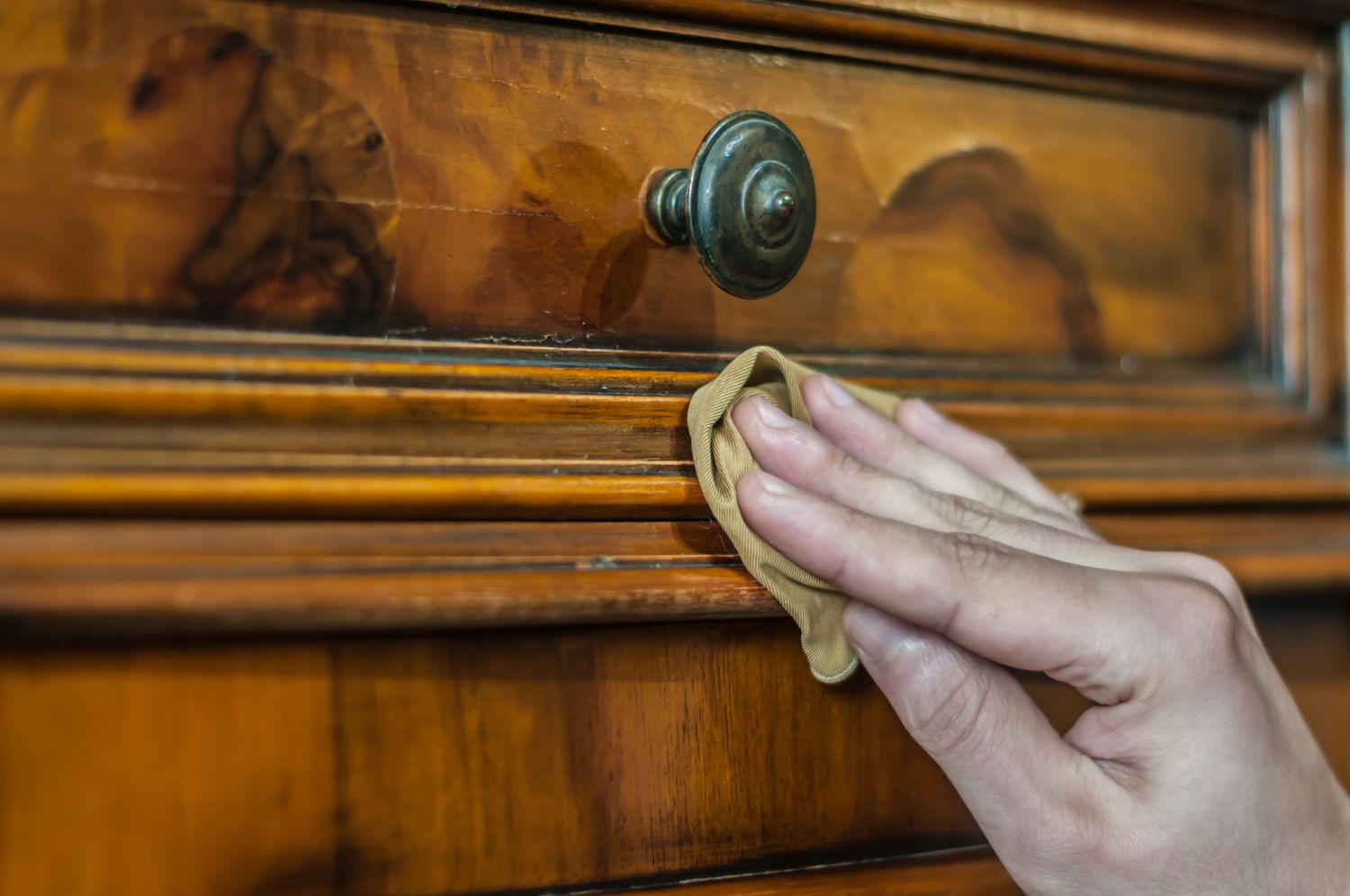 Close up of wood furniture with a cleaning cloth