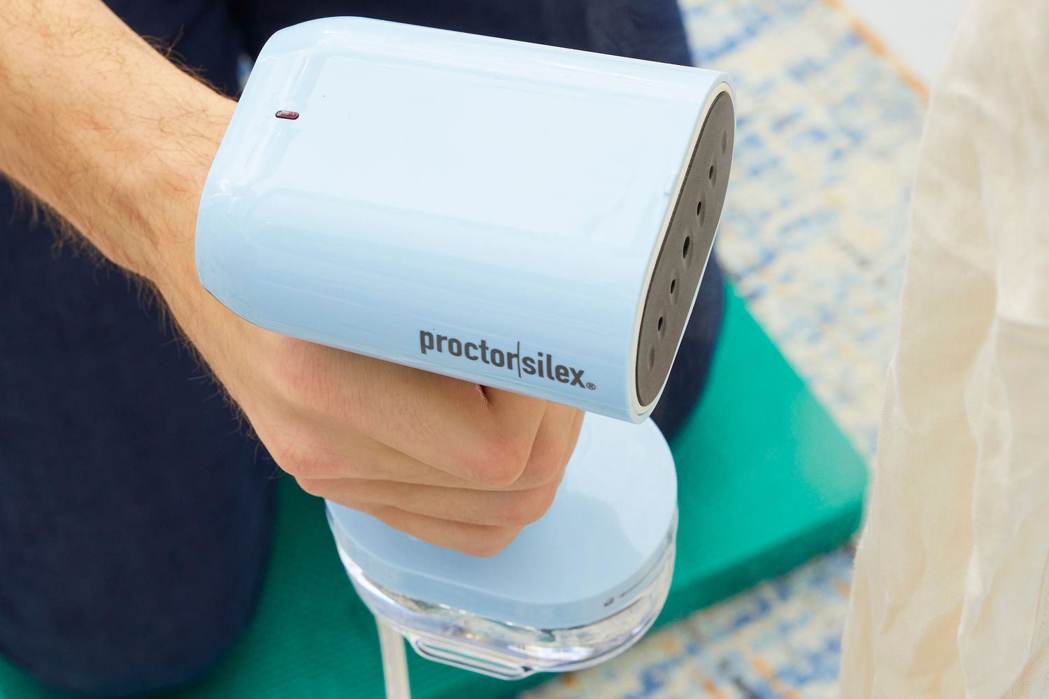 A close-up of the top of the Proctor Silex Compact 2-in-1 Garment Steamer/Iron while a person is holding it.