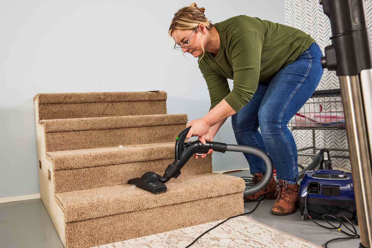 A person vacuums carpeted stairs using the Riccar Prima Power Team with Full-Size Nozzle R50FSN.4 Vacuum
