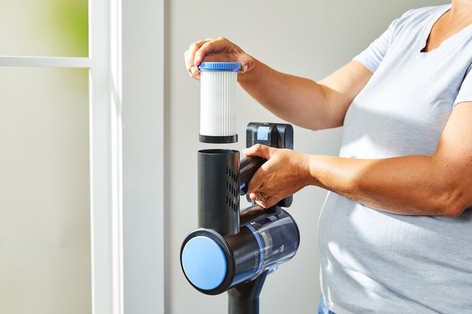 A close-up of a person pulling the filter out of the top of the WOWGO Cordless Vacuum Cleaner.