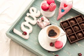 Wooden Tray With Valentine's Day desserts, coffee, and a "love" sign for celebrating Valentine's at home