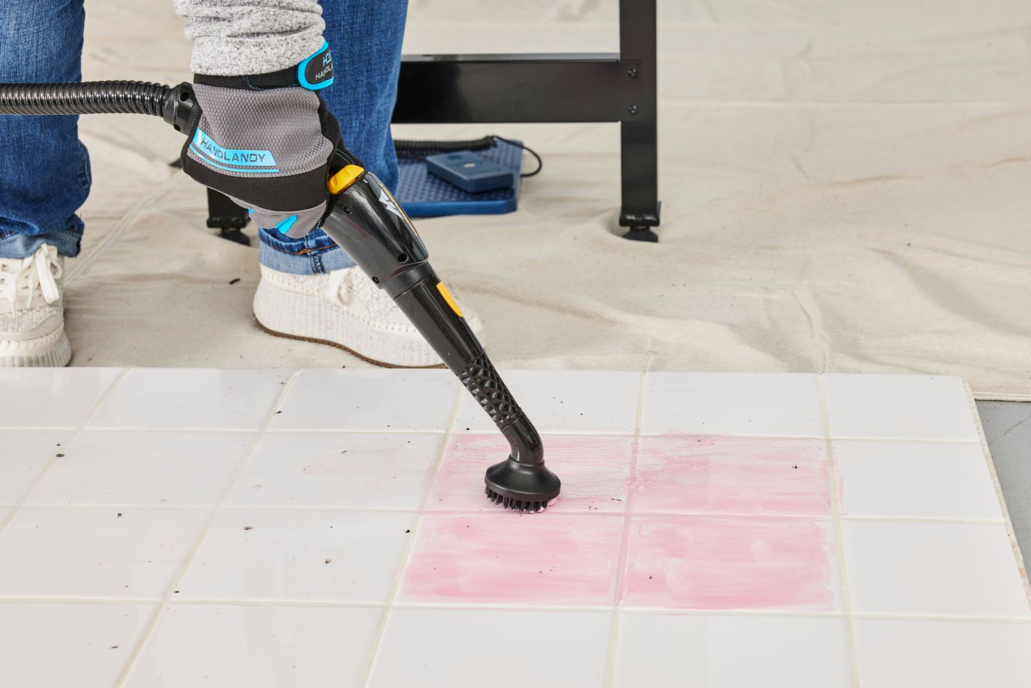 A person uses a brush attachment on the McCulloch MC1385 Deluxe Canister Steam Cleaner to clean a tile floor