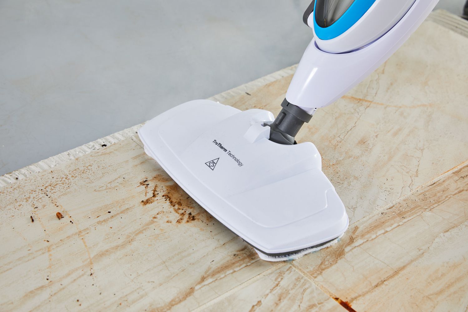 Closeup of the head of the PurSteam 10-in-1 Steam Mop cleaning a brown stain on a wood floor