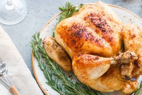 whole roasted chicken cooked in a convection oven and served on a white plate with rosemary