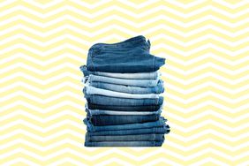 Stack of thirteen folded jeans in different shades against a yellow and white chevron pattern