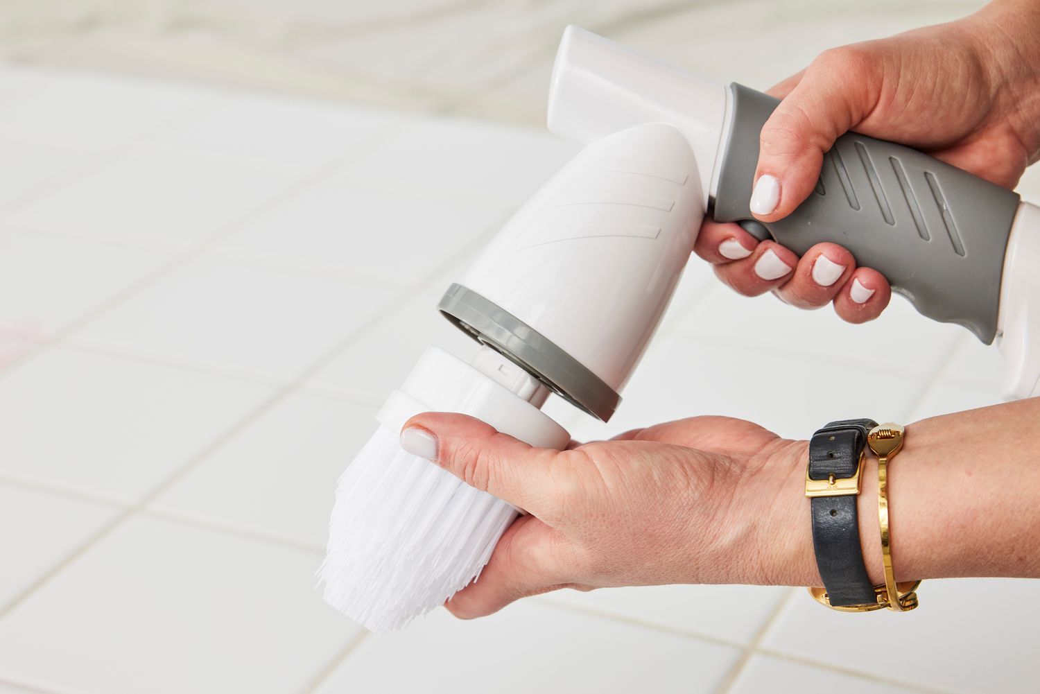 Hands holding a IEZFIX Electric Spin Scrubber over white tile