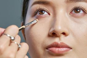 A makeup artist at work applying concealer under a model's eyes