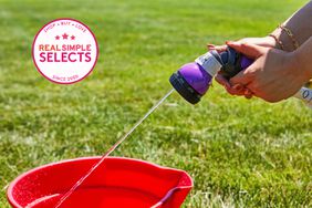 Hands using the Dramm Revolution 9-Pattern Spray Gun to fill a red bucket with water