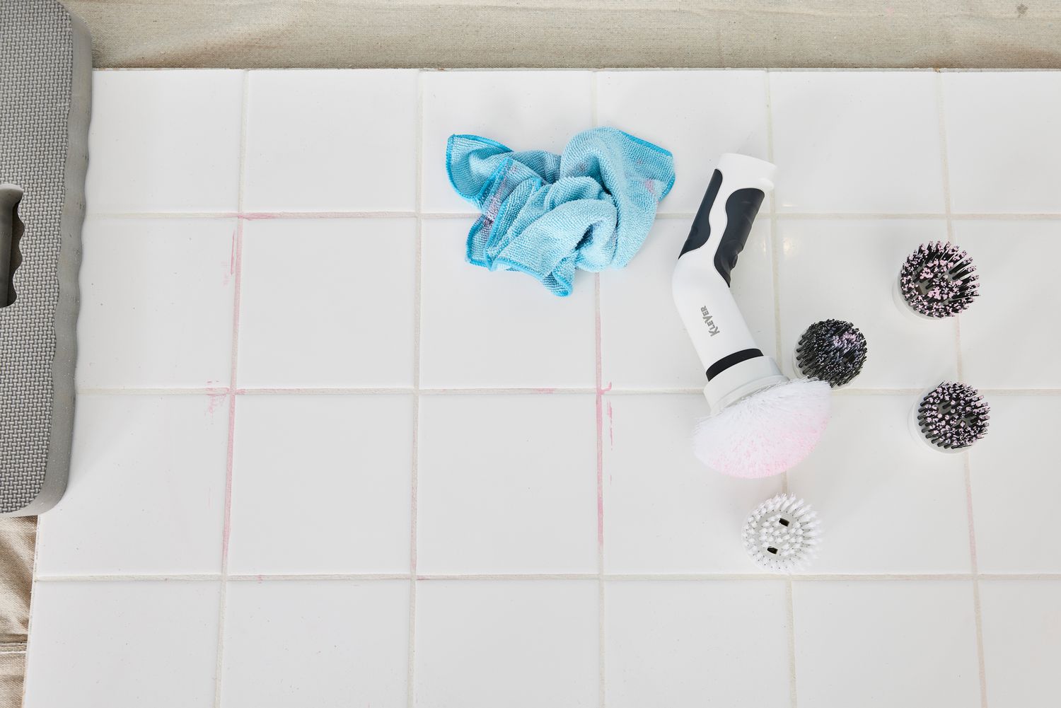 A Klever Electric Spin Scrubber with 8 Brushes lying on its side on white tile