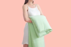 A person holding a folded Elegear Cooling Comforter over a peach background
