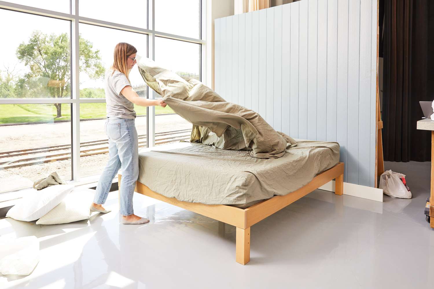 Person spreading the Parachute Percale Sheet Set on a bed 